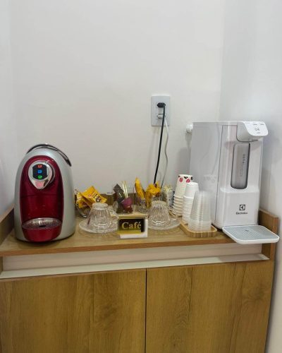 Mesa de Café na Recepção com máquina de café expresso, biscoitos e máquina de água.