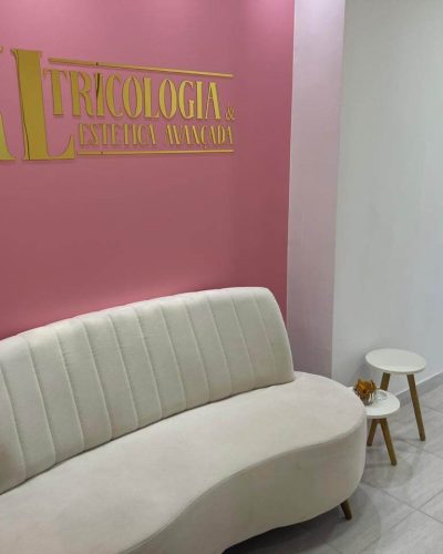Sala de recepção da Clínica de Estética Dra. Karen Lima mostrando um sofá, onde os pacientes podem esperar confortavelmente pelo seu atendimento. Logo acima do sofá esta o logotipo da clínica KL Tricologia e Estética Avançada